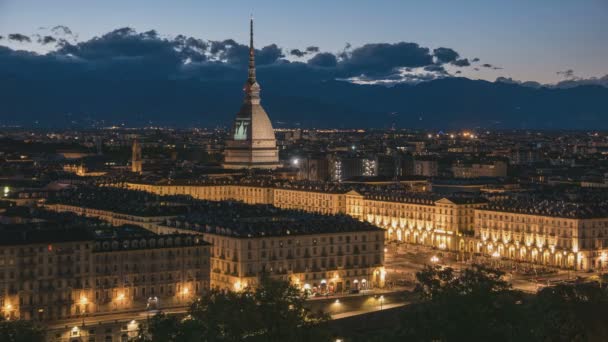 Torino (Torino, Olaszország)-skyline, a Mole Antonelliana épület fölé magasodó. TimeLapse gyengült a naplemente, alkonyat, fordult a város fényei. Mozgó felhők felett az Alpok — Stock videók