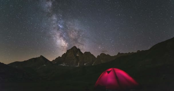 Time Lapse de la Vía Láctea y el cielo estrellado girando sobre los majestuosos Alpes franceses italianos en verano (M. Viso, 3841 m). Tienda de campaña iluminada en primer plano . — Vídeo de stock