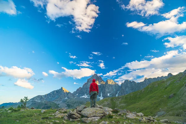 Una persona che guarda la maestosa vista delle cime delle montagne incandescenti al tramonto in alto sulle Alpi. Vista grandangolare posteriore, immagine tonica e filtrata . — Foto Stock
