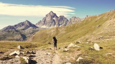     Kadın çiçek yeşil çayır yüksek irtifa kayalık dağ ve tepeler arasında geçiş patika üzerinde pastoral dağ manzarası içinde trekking. İtalyan Alpleri maceralara yaz. 