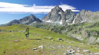     Kadın çiçek yeşil çayır yüksek irtifa kayalık dağ ve tepeler arasında geçiş patika üzerinde pastoral dağ manzarası içinde trekking. İtalyan Alpleri maceralara yaz. 
