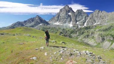     Kadın çiçek yeşil çayır yüksek irtifa kayalık dağ ve tepeler arasında geçiş patika üzerinde pastoral dağ manzarası içinde trekking. İtalyan Alpleri maceralara yaz. 