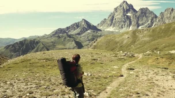 Žena, trekking v idylické horské krajině na chodník přes kvetoucí zelené louce uprostřed skalnatého pohoří vysoké nadmořské výšce a vrcholy. Letní dobrodružství na Italské Alpy. — Stock video