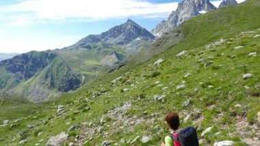 Kadın çiçek yeşil çayır yüksek irtifa kayalık dağ ve tepeler arasında geçiş patika üzerinde pastoral dağ manzarası içinde trekking. İtalyan Alpleri yaz maceralara. ağır çekim.