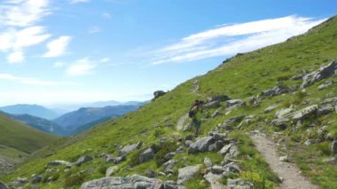 Kadın çiçek yeşil çayır yüksek irtifa kayalık dağ ve tepeler arasında geçiş patika üzerinde pastoral dağ manzarası içinde trekking. İtalyan Alpleri maceralara yaz.