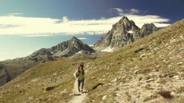 Kadın çiçek yeşil çayır yüksek irtifa kayalık dağ ve tepeler arasında geçiş patika üzerinde pastoral dağ manzarası içinde trekking. İtalyan Alpleri maceralara yaz.