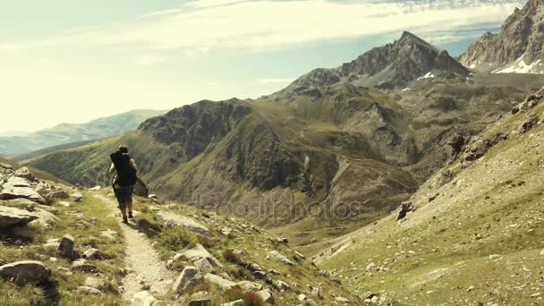 Mujer trekking en idílico paisaje de montaña en el sendero cruzando floreciente prado verde situado en medio de alta altitud cordillera rocosa y picos. Aventuras de verano en los Alpes italianos. cámara lenta . — Vídeos de Stock