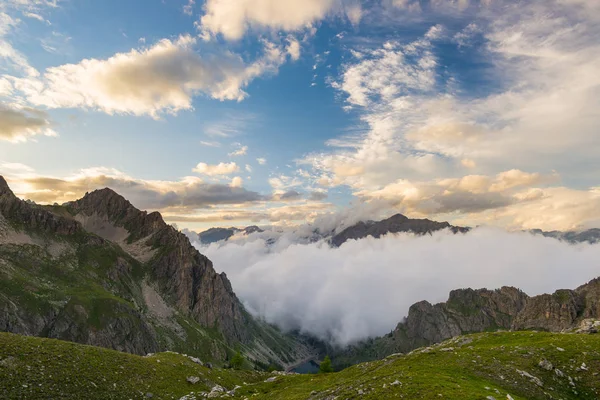 Letzte warme Sonneneinstrahlung im Alpental mit leuchtenden Berggipfeln und malerischen Wolken. Italienische Französische Alpen, Sommerreiseziel. — Stockfoto