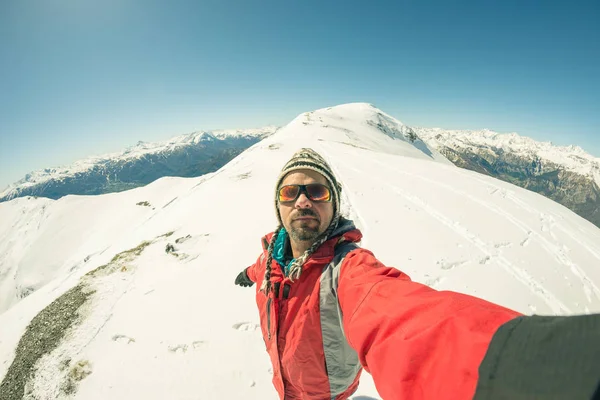 Erwachsener alpiner Skifahrer mit Bart, Sonnenbrille und Hut, der ein Selfie auf einer schneebedeckten Piste in den wunderschönen italienischen Alpen mit klarem blauen Himmel macht. Konzept von Fernweh und Abenteuer am Berg. Weitwinkelspalte — Stockfoto