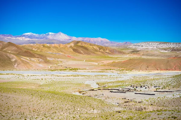 Высотная бесплодная горная цепь в высокогорье Анд на пути к знаменитой соляной равнине Уюни, одной из самых важных туристических достопримечательностей Боливии. Заброшенная старая деревня на плато — стоковое фото