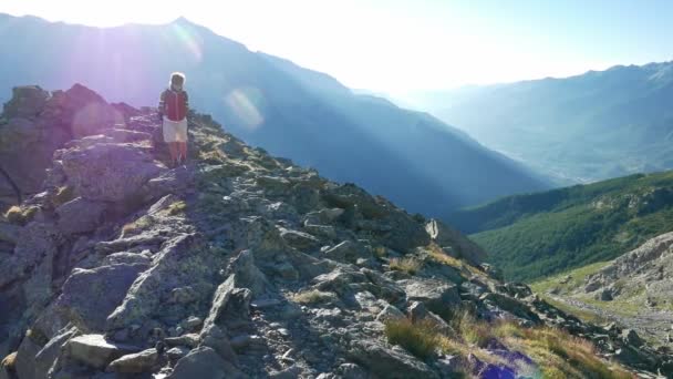 Vrouw wandeltochten in hooggelegen rotsachtige berglandschap. Zomer avonturen op de Italiaanse Franse Alpen. — Stockvideo