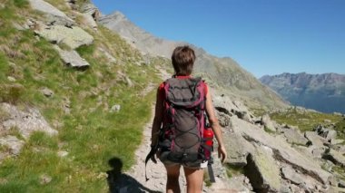 Kadın patika pastoral dağ manzarası, hiking. Alpler yaz maceralara. Ağır çekim, arka görüş ve kamera Pov.