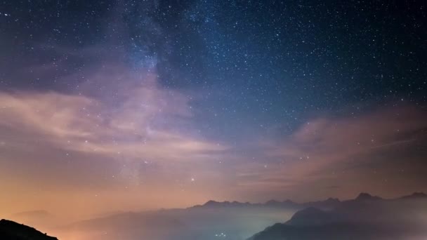Временной отрезок Млечного пути и звездное небо, движущееся над Итальянскими Альпами с туманом и влагой, приводящее к сновидному эффекту. Светящиеся долины внизу. Раздвижная версия . — стоковое видео