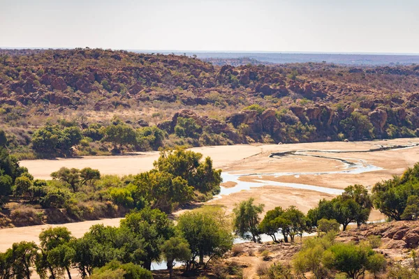 Fluss durch die Wüstenlandschaft des Mapungubwe Nationalparks, Reiseziel in Südafrika. Geflochtene Akazien und riesige Baobab-Bäume mit roten Sandsteinklippen. — Stockfoto