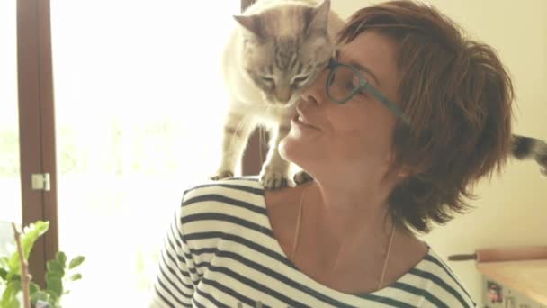Домашний кот играет на плече улыбающейся красивой женщины. В помещении. Тонированное изображение, винтажный стиль, ретро фильтр, подсветка. Медленное движение — стоковое видео