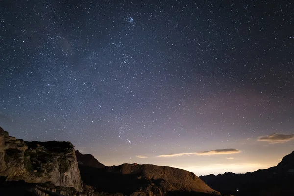 Este az Alpok, a csillagos ég és a fenséges sziklás sziklák az olasz Alpok, az Orion csillagkép a láthatáron:. — Stock Fotó