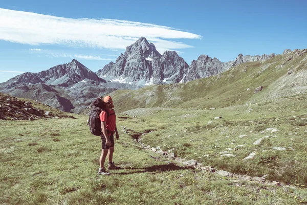 Una persona mirando la majestuosa vista de los picos de las montañas brillantes al atardecer en lo alto de los Alpes. Vista trasera, imagen tonificada y filtrada, enfoque en el fondo . — Foto de Stock