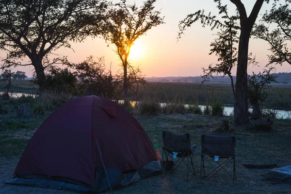 Kamp çadır, sandalye ve kamp malzemeleri. Sunrise Okavango Nehri, Namibya Botsvana sınırının üzerinde. Macera seyahat ve açık hava etkinlikleri Afrika. Tonlu görüntü, vintage tarzı. — Stok fotoğraf