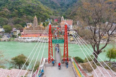Rishikesh, Hindistan - 8 Mart 2017: Hindu din için Rishikesh, Hindistan, kutsal şehir ve Yoga dersleri için ünlü hedef asma yaya köprüsü üzerinde Ganj nehri geçerken insanlar.