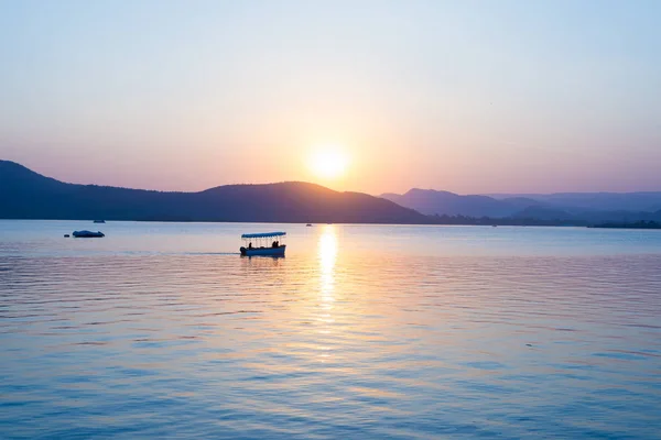 Renkli Günbatımı ile PICHOLA Lake üzerinde yüzen tekne tepeler üzerinde su öteye reflated. Udaipur, Rajasthan, Hindistan. — Stok fotoğraf