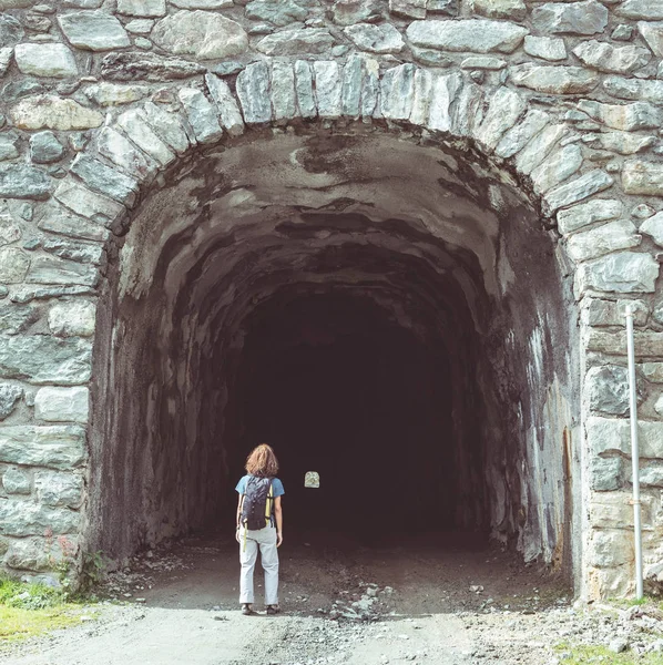 Woman walking at tunnel entrance. Toned image, vintage filter, split toning. — Stock Photo, Image