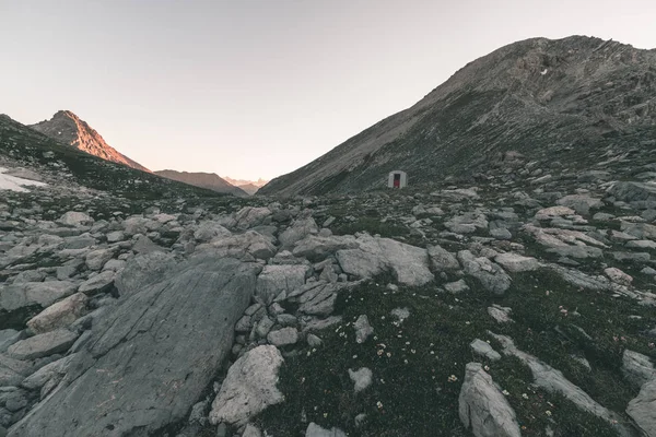 Prado alpino e pasto situado em meio a alta altitude gama de montanhas ao pôr do sol. Os Alpes italianos, famoso destino de viagem no verão. Imagem dentada, filtro vintage, tonificação dividida . — Fotografia de Stock