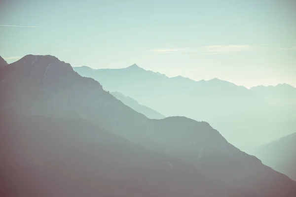 Distant mountain silhouette with clear sky and soft light. Toned image, vintage filter, split toning. — Stock Photo, Image