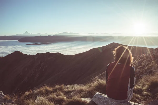 Senderista que llega a su meta en la cima de la montaña y mira a la majestuosa vista panorámica de los Alpes con pico de montaña en el fondo. Amplia vista angular al atardecer en contraluz, imagen tonificada, vintage —  Fotos de Stock