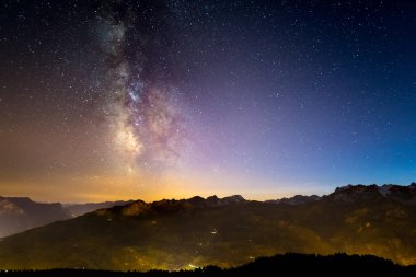 The colorful glowing Milky Way and the starry sky over the French Alps and the majestic Massif des Ecrins. clipart