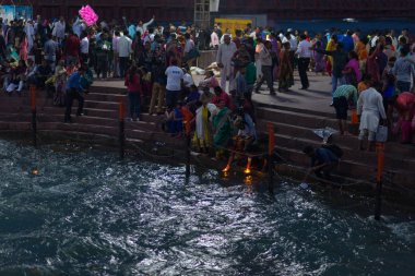 Haridwar, Hindistan - 20 Mart 2017: Haridwar, Hindistan 'da kutsal ghat, Hindu dini için kutsal kasaba. Hacılar Ganj Nehri 'ne çiçekler ve yanan mumlar sunuyor..