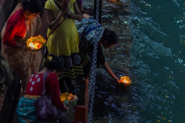 Haridwar, Hindistan - 20 Mart 2017: Haridwar, Hindistan 'da kutsal ghat, Hindu dini için kutsal kasaba. Hacılar Ganj Nehri 'ne çiçekler ve yanan mumlar sunuyor..