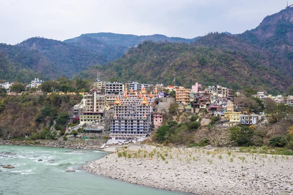 Cityscape of Rishikesh at sunset, holy town and travel destination in India. Colorful sky and clouds reflecting over the Ganges River. — Stock Photo, Image
