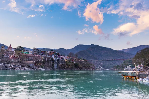 Paisaje urbano de Rishikesh al atardecer, ciudad santa y destino de viaje en la India. Cielo colorido y nubes reflejándose sobre el río Ganges . —  Fotos de Stock