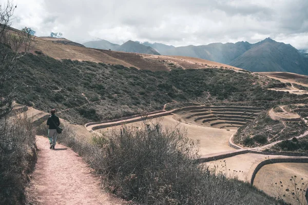 Turista explorando el sitio arqueológico en Moray, destino turístico en la región del Cusco y el Valle Sagrado, Perú. Majestuosas terrazas concéntricas, supuesto laboratorio de cultivo de alimentos Inca . — Foto de Stock
