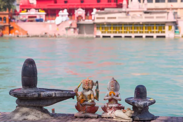 Hindu vallási szimbólumok a Gangesz folyó, Szent vizek partján. Shiva szobor és lingam. Defocused templom. — Stock Fotó