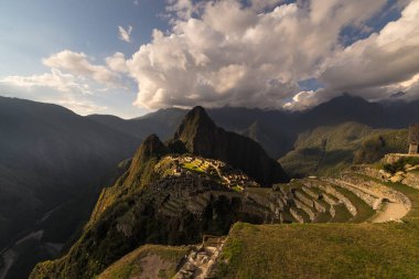 Machu Picchu sıcak gün batımı ışıkla aydınlatılmış. Teraslar üzerinde gökyüzü ve güneş patlaması ile geniş açılı manzara. Rüya seyahat hedef, dünya harikası. Cusco bölgesinde, Peru.