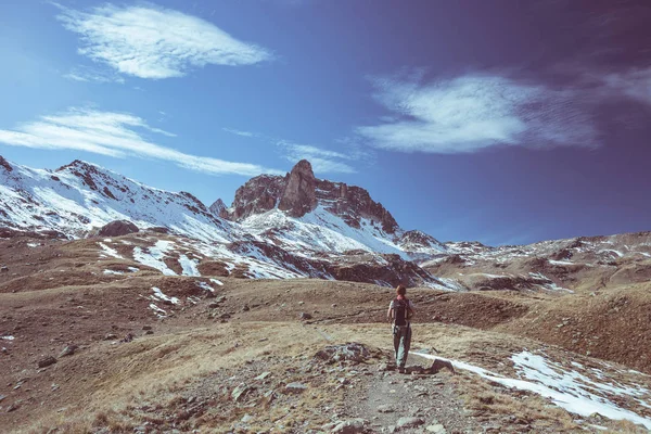 Caminhante olhando para a excelente vista da paisagem de alta altitude e majestoso pico de montanha coberto de neve na temporada de outono. Tiro de ângulo largo nos Alpes franceses italianos. Imagem descontrastada tonificada . — Fotografia de Stock