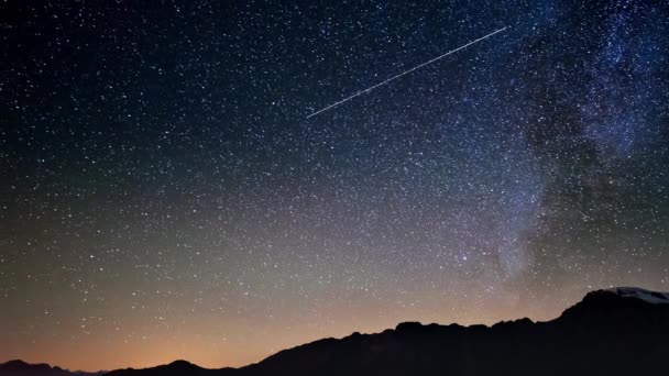 Scenic meteor explosion with stardust during time lapse of the Milky Way and the starry sky rotating over the Alps. — Stock Video