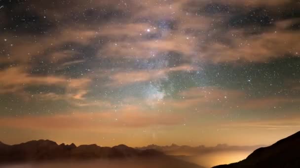 Tidsfördröjning för av Vintergatan och den stjärnklara himlen med moln över Alperna och den majestätiska Massif des Ecrins, Frankrike. Bardonecchia Valley belysta i dimman, Italien. — Stockvideo