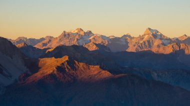 Alpler üzerinden günbatımı. Renkli gökyüzü, Fransa buzullar, Massif des Ecrins Milli Parkı, yüksek dağ zirveleri. Telefoto görünümden uzak.
