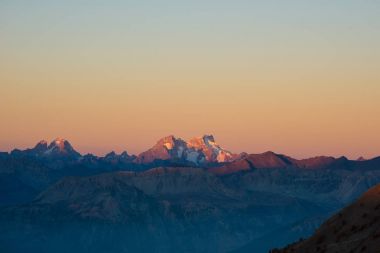 Alpler üzerinden günbatımı. Renkli gökyüzü, Fransa buzullar, Massif des Ecrins Milli Parkı, yüksek dağ zirveleri. Telefoto görünümden uzak.
