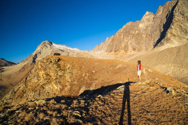 Uma pessoa a olhar para a vista no alto dos Alpes. Paisagem extrovertida, vista idílica ao pôr-do-sol. Vista traseira . — Fotografia de Stock