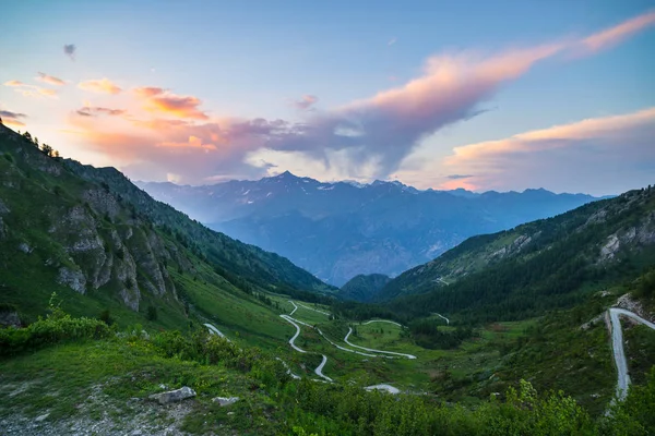 Gebirgsstraße, die zum Hochgebirgspass in den italienischen Alpen führt. Expasive Aussicht bei Sonnenuntergang, farbenfroher dramatischer Himmel, Abenteuer-Roadtrip im Sommer. — Stockfoto