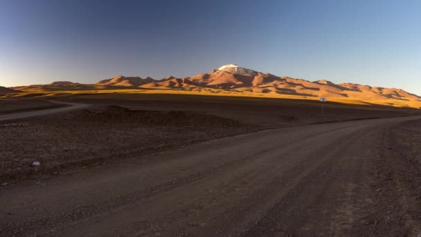 Das andenpanorama bei untergang, straßenfahrt zwischen bolivien und chile. 4x4 Straße im menschenleeren Andenhochland mit schneebedecktem Berggipfel, Bolivien. — Stockvideo