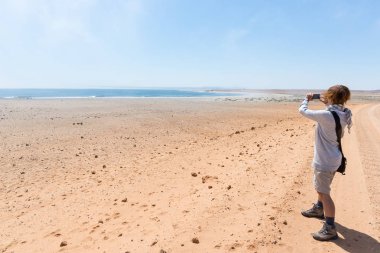 Turist Cape çapraz, Namibya, Atlantik Okyanusu ile akıllı telefon çekim sahilde. Açık mavi gökyüzü.