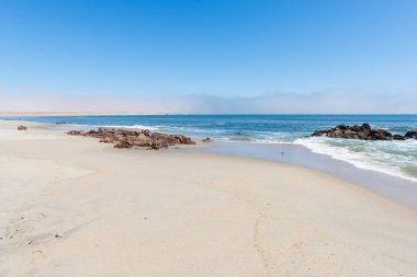 Kumsal ve Atlantik Okyanusu kıyısındaki Cape Cross, Namibya, yakındaki fok kolonisiyle ünlüdür. Açık mavi gökyüzü.