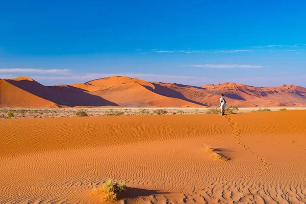 Tourist walking on the sand dunes at Sossusvlei, Namib desert, Namib Naukluft National Park, Namibia. Traveling people, adventure and vacations in Africa. — Stock Photo, Image