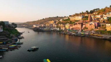 Günbatımı zaman atlamalı Omkareshwar cityscape, Hindistan, kutsal hindu Tapınağı. Kutsal Narmada nehir, yüzen tekne. Turistler ve hacılar için seyahat hedef.