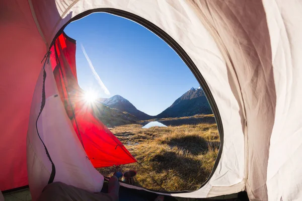 Acampar com tenda nos Alpes. Vista do interior da tenda ao nascer do sol, parte do corpo. Aventura e exploração, atividade ao ar livre . — Fotografia de Stock