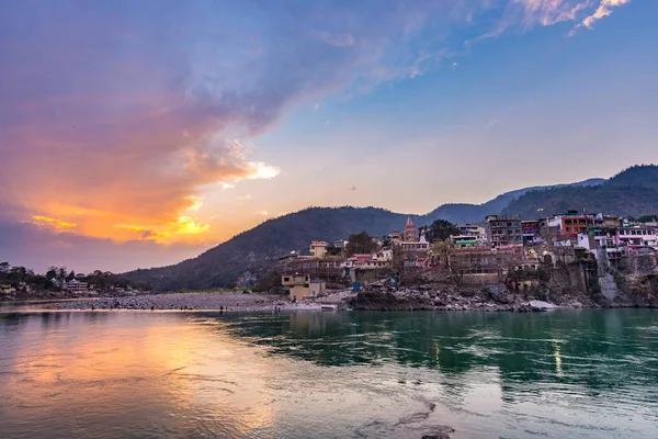 Hora del anochecer en Rishikesh, ciudad santa y destino de viaje en la India. Cielo colorido y nubes reflejándose sobre el río Ganges . —  Fotos de Stock